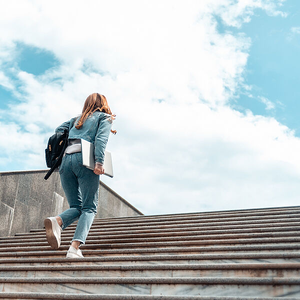 Studentin läuft eine steinerne Treppe nach oben