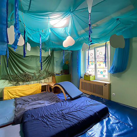 The cosy room is equipped with mattresses and loungers in a cosy blue interior.