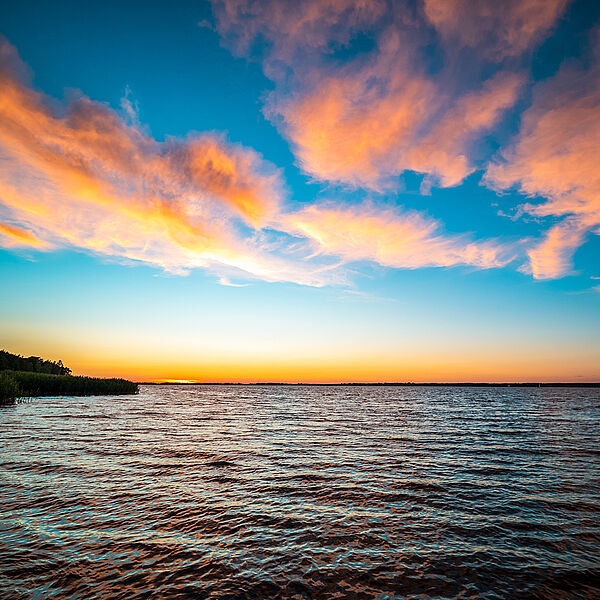 Sonnenaufgang über dem See mit orangen Wolken