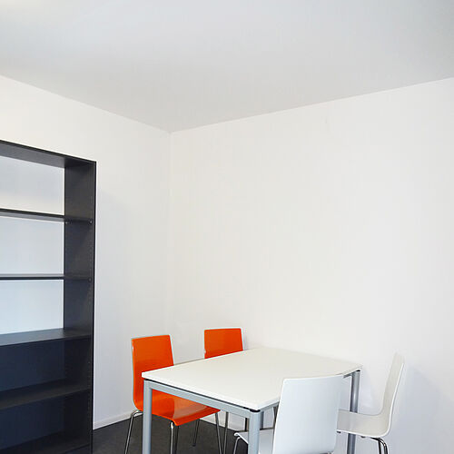 Heller Gemeinschaftsraum mit Tisch, vier Stühlen und Regal in einem Seezeit-Wohnheim