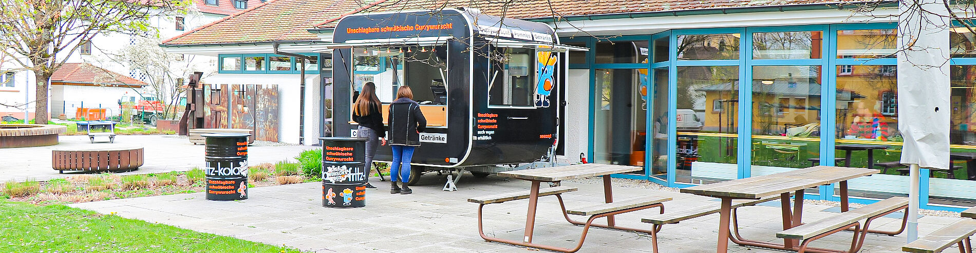 Terrace of Mensa Weingarten with food trailer "WurschtBox", two people standing in front of it