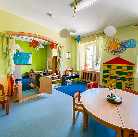 Bright ‘Wiesenland’ room with green walls, a table, chairs and plenty of space to play