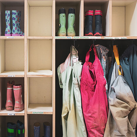 Gummistiefel und Regenhosen an der Garderobe